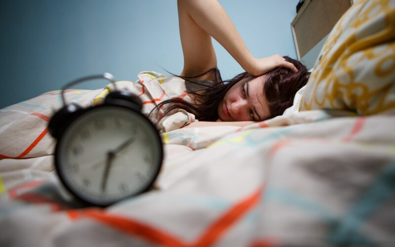 Woman waking up to an early alarm after not enough sleep