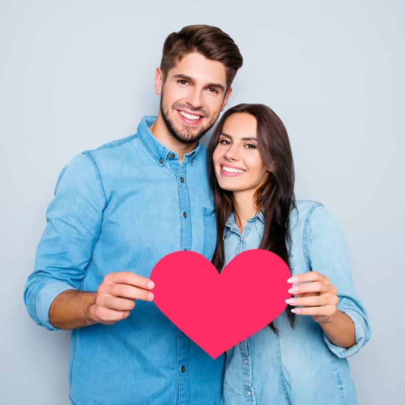 Happy couple holding love shape card